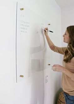 a woman is writing on a white board