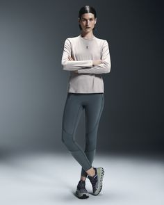 a woman is standing with her arms crossed and looking at the camera while wearing running shoes