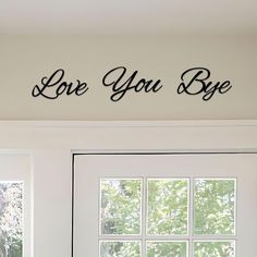 love you bye wall decal above a door in a room with white walls and windows