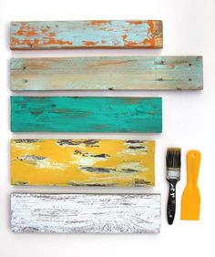 three different colored wood planks and a paintbrush