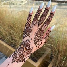 a woman's hand with henna on it and some grass in the background