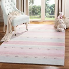 a white chair sitting on top of a wooden floor next to a pink and blue rug