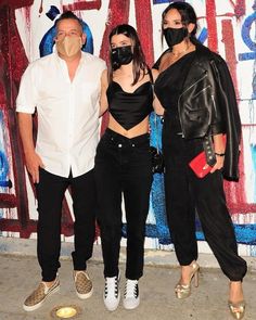 three people standing next to each other wearing masks