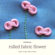 an image of some pink flowers made out of yarn on a piece of blue fabric