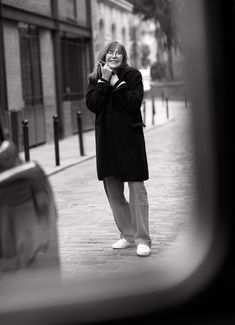 a woman standing on the sidewalk talking on her cell phone