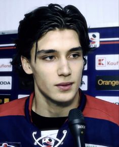 a young man holding a microphone in front of a wall with other signs on it