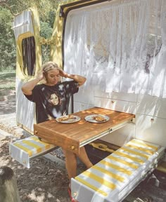 a woman sitting at a picnic table in the back of a campervane