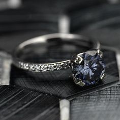 a diamond ring sitting on top of a piece of black and white wood with diamonds around it