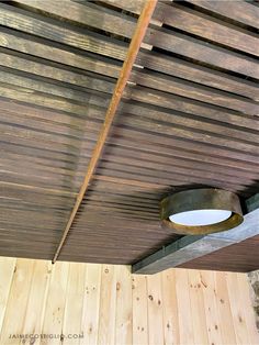 the ceiling is made out of wood planks and has a circular light fixture hanging from it