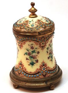 an ornately decorated porcelain jar with gold trimmings and blue flowers on it