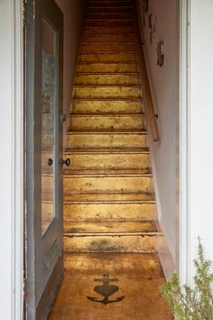 an open door leading to a set of stairs with a cross painted on the floor