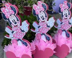 three pink minnie mouse cupcake toppers on display in front of potted plants