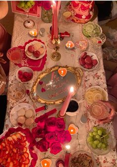 the table is set with candles, plates and fruit for valentine's day dinner