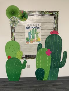 two green cactuses are sitting in front of a bulletin board that says, i am miss class we stuck together