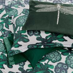 a green and white bed spread with dragonfly pillow cases on it's sides