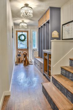 two dogs are sitting on the stairs in this entryway with built - in bookshelves