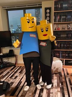 two people in lego costumes standing next to each other with their arms around each other