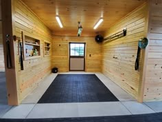 the inside of a wooden building with black mats on the floor and wood paneling