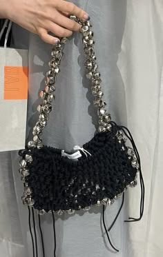 a woman holding a black purse with silver beads