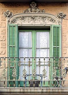 an ornate balcony with green shutters and wrought iron railing