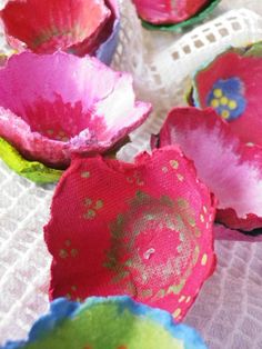 some pink and green paper flowers on a white table cloth with doily around them