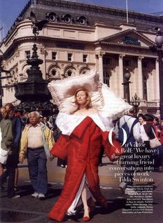 a woman in a red and white dress is walking down the street with pillows on her head