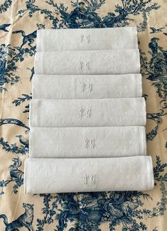 six white towels laid out on top of a blue and white flowered table cloth