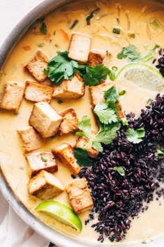 a bowl filled with rice, tofu and garnished with cilantro