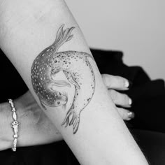 a woman's arm with a tattoo on it that has a fish in the middle