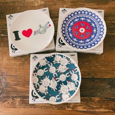 three plates with designs on them sitting on a wooden table