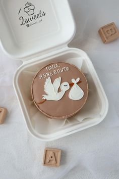 a stork and baby shower cake in a plastic container with wooden blocks on the side