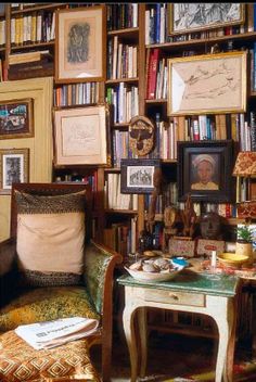 a living room filled with lots of books and pictures on the wall next to a couch