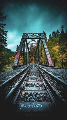 an old train track with graffiti on it and trees in the backgrouds