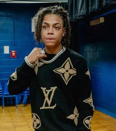 a woman in a black and gold louis vuitton sweater posing for the camera