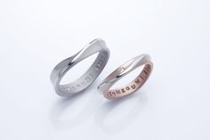 two wedding rings with the word love written on each side and an inscription engraved in pink gold