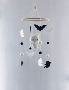 a white teddy bear hanging from a ceiling mobile with bats on it's sides