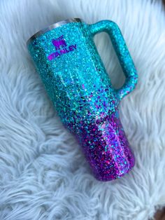 a blue and purple glittered cup sitting on top of a white fur covered floor