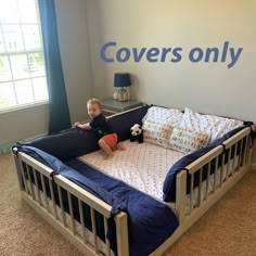 a little boy sitting on top of a bed in a room with carpeted floors