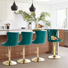 three green velvet barstools with gold legs in a modern kitchen, with a cat sitting on the bar