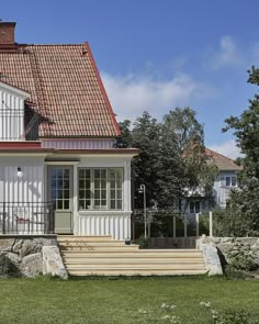 a white house with a red roof and steps leading up to the front porch area