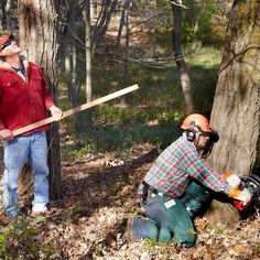 two men in the woods with chainsaws on their hands and one holding a stick