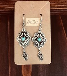 Silver look Floral Western wire earrings with tiny dangle with dream catcher. Perfect for the cowgirl in your life, young or old! Turquoise colored stone sits in middle of floral scalloped design. Custom made by Old Hands Creations. Made from zinc alloy and silver plate.  Please check out our other items as some are complimentary to this item. If you buy 2 or more items you will get 15% off, spend $50 and get 20% off. Pay only one shipping cost for multiple items. We take custom order requests a Western Jewelry Earrings, Scalloped Design, Feather Dream Catcher, Old Hands, Earrings Turquoise, Colored Stones, Colored Stone, Cow Girl, Western Jewelry