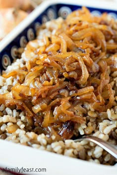 rice and onions are mixed together in a blue bowl on top of the tablecloth