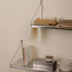 two metal shelves holding books and bowls on top of each other in a white room