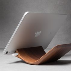 an apple ipad with a wooden stand on it's side, in front of a gray background