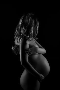 a black and white photo of a pregnant woman's body with her hands on her hips