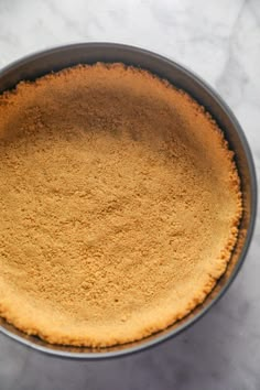 a pie crust in a metal pan on a marble counter top with a white background