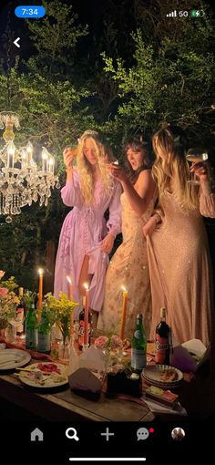 three women standing around a table with candles on it