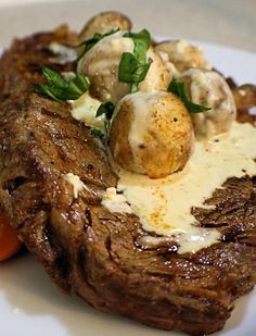 a piece of steak covered in cheese and mushrooms