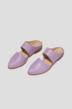 The mule is ZX’s perennial flat, inspired by traditional babouche slippers. With its sleek cut-out upper and almond shaped toe, this style makes feeling comfortable and pulled-together an easy task for days filled with lots of activity. This pair is crafted from vibrant lilac kidskin. Style yours with statement pants for a chic party look. Who it’s for: The woman with refined style who likes to go places by foot. Kidskin leather upper and undyed vegetable-tanned leather lining. Leather sole and stacked heel. Handmade in Argentina. Chic Spring Slides With Rubber Sole, Chic Slides With Rubber Sole For Spring, Chic Slides With Rubber Sole, Modern Clogs With Flat Heel For Spring, Modern Closed Toe Slides For Spring, Chic Slippers With Rubber Sole And Flat Heel, Modern Closed Toe Mules For Spring, Spring Slip-on Pointed Toe Clogs, Slip-on Pointed Toe Clogs For Spring